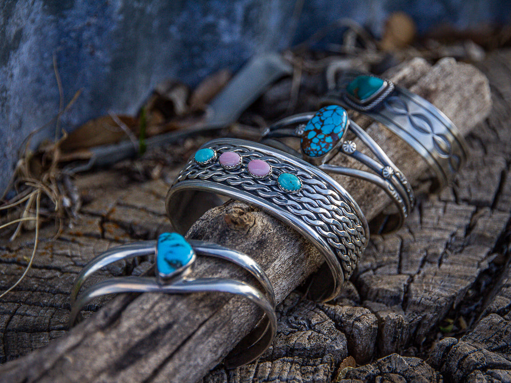 Silver bracelets with colorful gemstones on a wooden surface